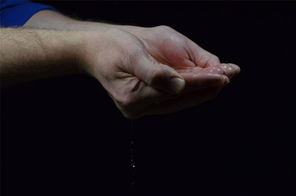 hands holding some water under lights with a fast shutter speed of 13200